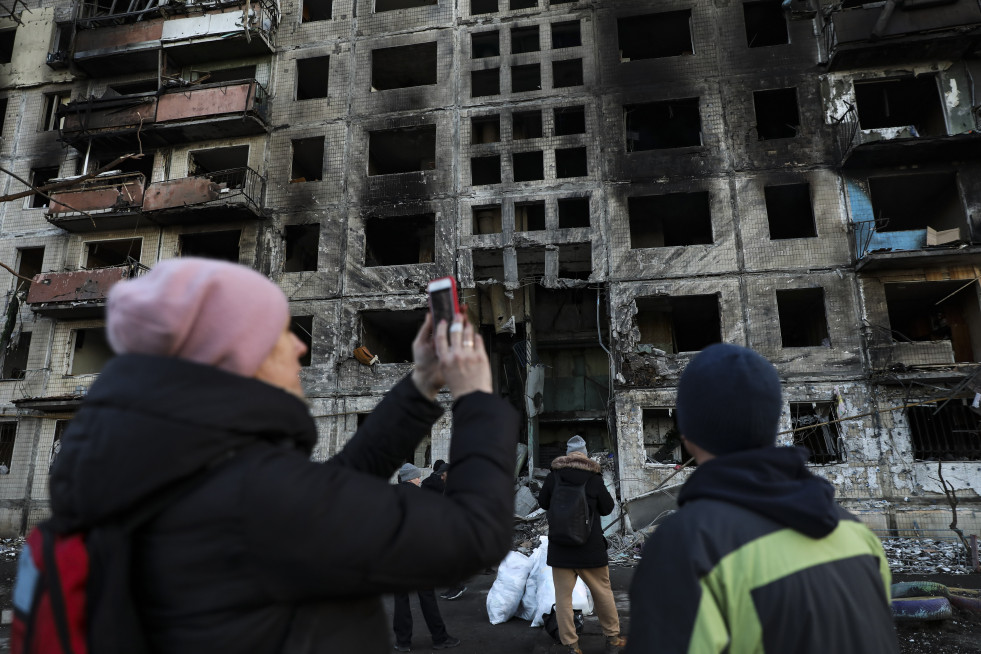 Una mujer toma fotos con su móvil de un edificio destrozado por los bombardeos en Kiev